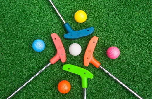 four mini golf putters with balls